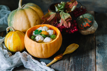 Soup in a pumpkin with different pumpkins for autumn dinner