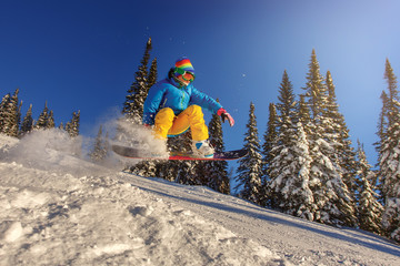 Snowboarder jumping against blue sky