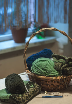 Knitted norway sweater with knitting needles and wool yarn in basket. Freelance, hobby, home concept