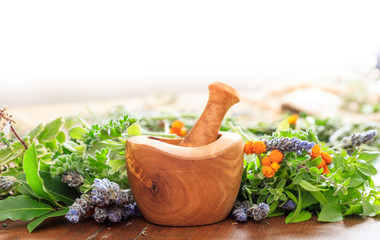 Variety of herbs and mortar on wooden background