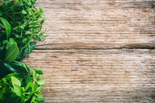 Variety of herbs on wooden background, top view, copy space