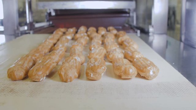 Conveyor line with moving Eclairs. Eclairs, cakes, pastry, dessert production line 4K
