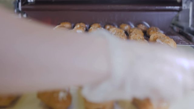 Conveyor line with moving Eclairs. Hands putting eclairs, cakes, pastry, desserts on a production line. 4K.