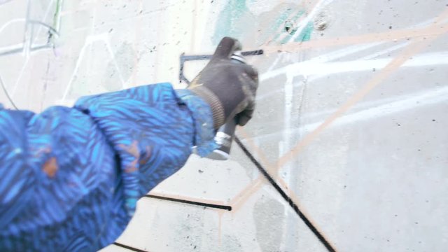 Graffiti artist painting on the wall, exterior, close up