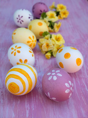 Easter eggs and primrose bouquets on the violet board