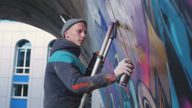 Graffiti artist painting on the wall, exterior