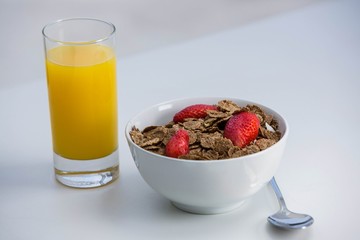 View of bowl of cereals and orange juice