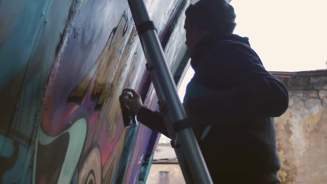Graffiti artist painting on the wall, exterior