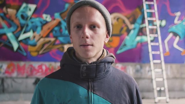 Graffiti artist smoking cigarette and watching at his work
