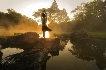 Fototapeten Young woman in silhouette practice yoga in a hot spring © ID_Anuphon