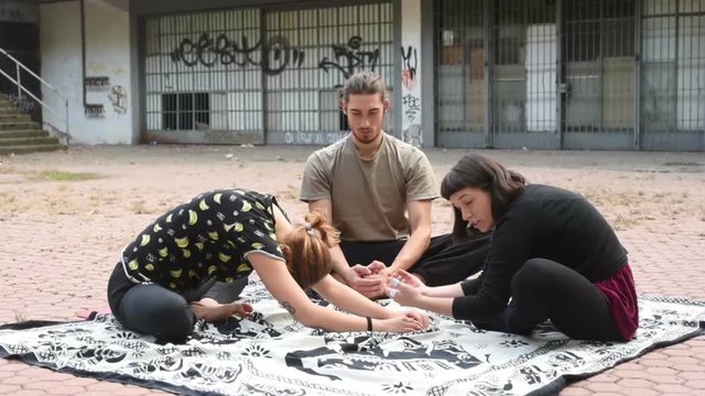 Three young beautiful caucasian woman and men friedns training outdoor in the city - sportive, yoga, fitness concept