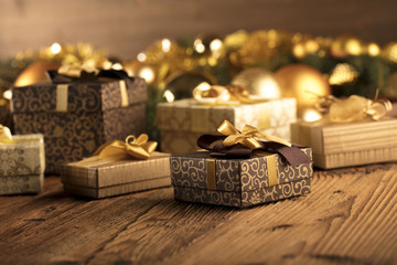 Golden Christmas decoration. Presents in boxes on a wooden background with copy space. Golden baubles. Christmas theme. Golden and brownish aesthetics. Christmas spices.