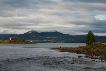 The river flowing from the lake and a house on the shore. Lake Labynkyr. Yakutia. Russia.