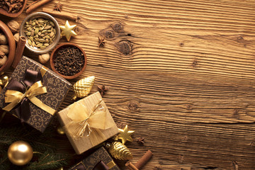 Golden Christmas decoration. Presents in boxes on a wooden background with copy space. Golden baubles. Christmas theme. Golden and brownish aesthetics. Christmas spices.