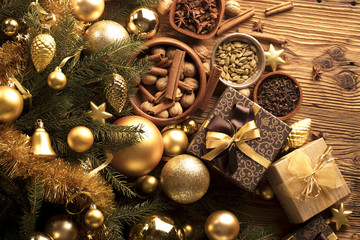 Golden Christmas decoration. Presents in boxes on a wooden background with copy space. Golden baubles. Christmas theme. Golden and brownish aesthetics. Christmas spices.