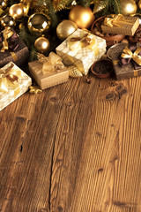 Christmas theme, christmas decoration. presents in boxes on a wooden table with golden baubles, clove, cardamon, star anise, cinnamon. Golden and brownish aesthetics. Place for typography and logo.