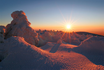 Sonnenaufgang, tief verschneite Winterlandschaft auf dem Gipfel des Brockens im Harz, schneegebeugte Bergfichten