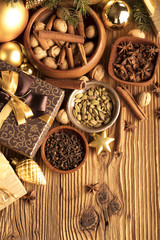 Christmas theme, christmas decoration. presents in boxes on a wooden table with golden baubles, clove, cardamon, star anise, cinnamon. Golden and brownish aesthetics. Place for typography and logo.