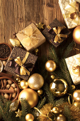 Christmas theme, christmas decoration. presents in boxes on a wooden table with golden baubles, clove, cardamon, star anise, cinnamon. Golden and brownish aesthetics. Place for typography and logo.