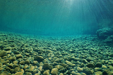 Pebbles underwater on riverbed with clear freshwater and sunlight through water surface, natural scene, Dumbea river, New Caledonia, south Pacific