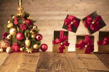 Golden presents with red ribbon under christmas tree. Wooden background and table. Red and gold. Place for typography and logo. Copy space.