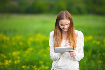 Young freckled girl agronomist or biologist in white blouse standing in green field with notebook and pen during harvest.