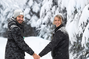 Young Man Couple Walking In Snow Forest Outdoor Guys Holding Hands Winter Pine Woods