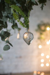 Green leaves of fern in hanging glass water tubes. Pieces of beautiful rustic wedding decoration. Loft style wedding. Blurred background.