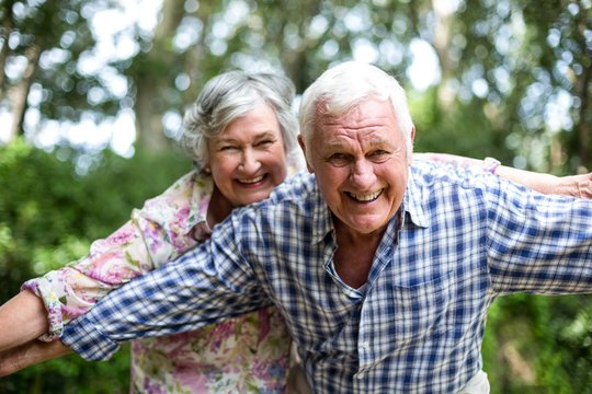 Happy senior couple with arms outstretched in back yard