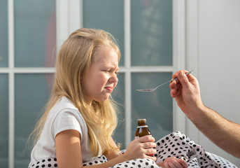 Sick  girl in bed taking medicine
