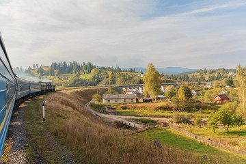 Obraz premium View from the train window at the sunlit village. Carpathians, U