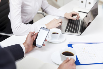 Man looking at his phone, woman typing in office