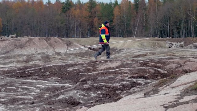 Land surveyor assistant in uniform works with levelling rod on construction site