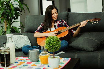 Brunette woman at home playing the guitar