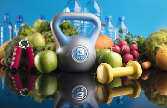 Diet and Fitness theme with healthy food. Place for typography and logo. Beautiful reflections. Bright blue background. Lots of vegetables, fruits and fitness equipment. Healthy lifestyle concept.