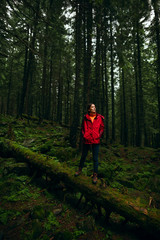 Obraz premium Woman hiking. Hike in the mountains. Woman traveler with backpack on beautiful landscape. Young woman tourist walking along the trail in the rain forest.