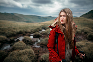 Shot of a young woman looking at the landscape while hiking in the mountains.Outdoor shot of attractive young woman with backpack standing in a mountain stream. Female hiker in creek water.