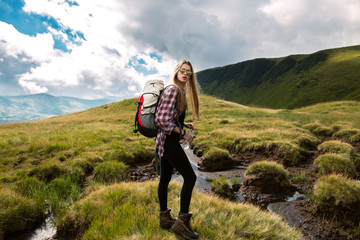 Naklejka na ściany i meble Shot of a young woman looking at the landscape while hiking in the mountains.Outdoor shot of attractive young woman with backpack standing in a mountain stream. Female hiker in creek water.