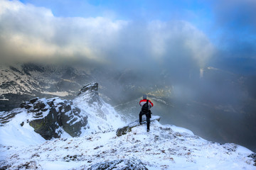 Hiker standing on a rock.Winter landscape.Climber on the snowy mountains.Travel inspiration and motivation, beautiful landscape.Active sport concept