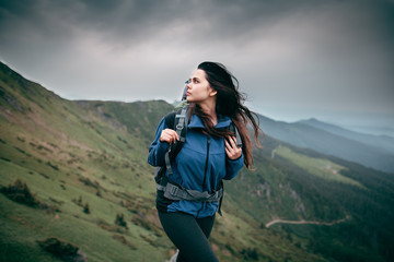 Shot of a young woman looking at the landscape while hiking in the mountains. Hair blowing in the wind