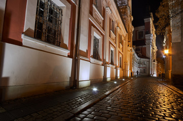 Paved street and buildings of the former monastery during the night in Poznan.