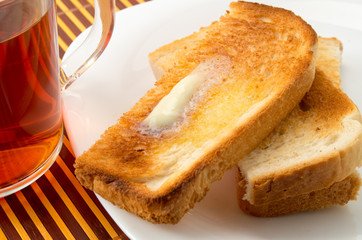 Hot toast with butter on a white plate close-up