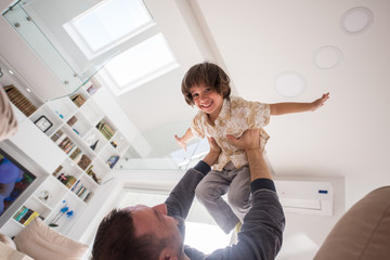 Cheerful young boy having fun with father on sofa