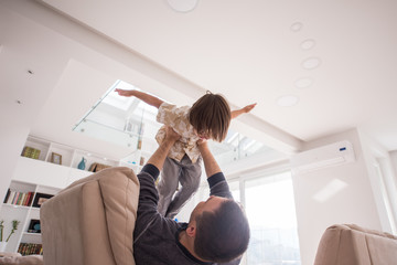 Cheerful young boy having fun with father on sofa