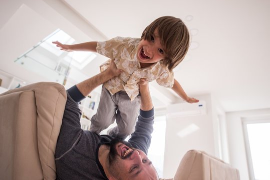 Cheerful young boy having fun with father on sofa