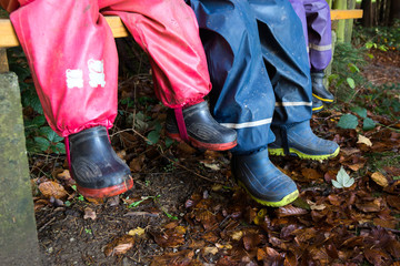 Kinder mit bunten Gummistiefeln und Regenhose