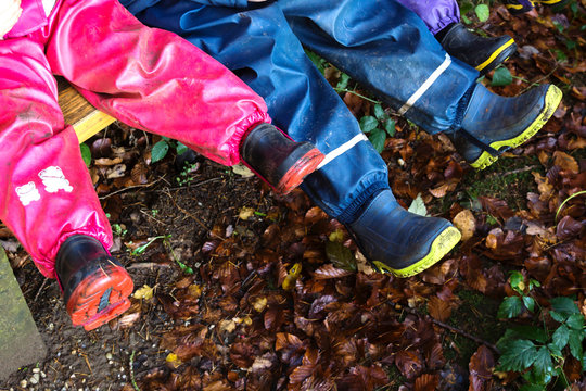 Kinder mit bunten Gummistiefeln und Regenhose
