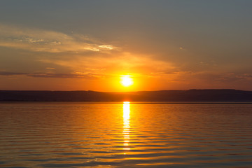 Sunrise over the distant shore. Dawn. The sun over the water.