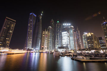Fototapeta na wymiar Architecture theme. Dubai marina. Luxurious travel and living, business and finance theme. Luxurious apartments. High value property. Night lights. Illuminated skyline. Big construction site.