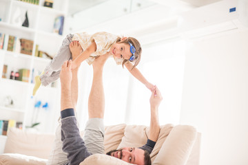 Father playing with his little son on sofa at home